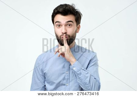 Hispanic Man Placing Finger On Lips As If To Say, Shhhhh, Be Quiet, Silence.