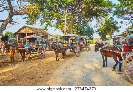 Ava, Myanmar - February 21, 2018: The Shady Street Is Occupied With Numerous Vintage Horse-drawn Car