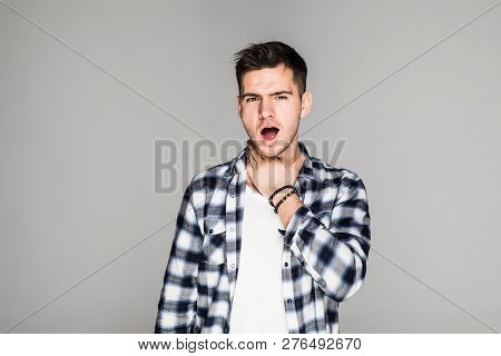 Young Man Having Sore Throat And Touching His Nec Against Grey Background.