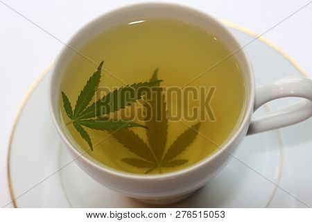 Cannabis Tea. Marijuana Tea. Hemp Tea with a Marijuana Leaf in a white Tea Cup. Isolated on white. Room for text. 