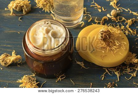 Facial Cream Of Calendula And Beeswax, On A Blue Wooden Background