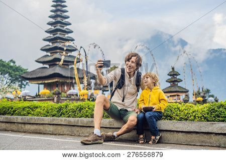 Dad And Son In The Background Of Pura Ulun Danu Bratan, Bali. Hindu Temple Surrounded By Flowers On 