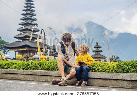 Dad And Son In The Background Of Pura Ulun Danu Bratan, Bali. Hindu Temple Surrounded By Flowers On 