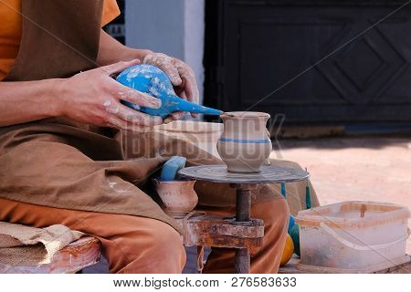 Potter Uses A Tool To Cover Clay Pot With Paint. Pottery And Craftsmanship Concept.