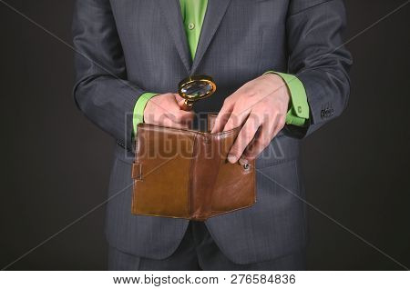 Businessman Is Looking For Money In His Empty Waller With Magnifying Glass In His Hand To Pay The Bi