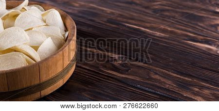 Potato Chips Lie In A Light Oak Tray On A Dark Table.