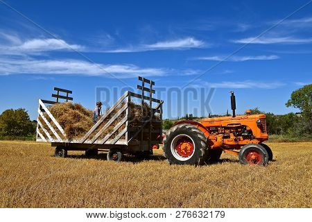Rollag, Minnesota, September 1, 2018: A Minneapolis Moline With A  Young Worker On Rack Of Bundles  