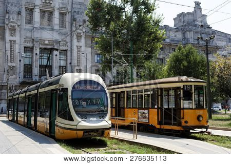 MILAN, ITALY - AUGUST 5, 2018: Modern and retro styled trams on piazza IV Novembre at Central train station. In operation since 1881, the Milan tram network is now 181.8 kilometers (113.0 mi) long