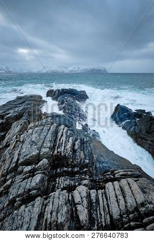Waves of Norwegian sea crushing at rocky coast in fjord. Vikten, Lofoten islands, Norway