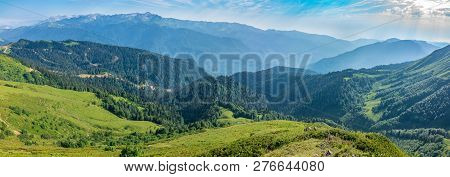 The View From The Height Of The Green Mountain Valley With A Cable Car, Surrounded By High Mountains