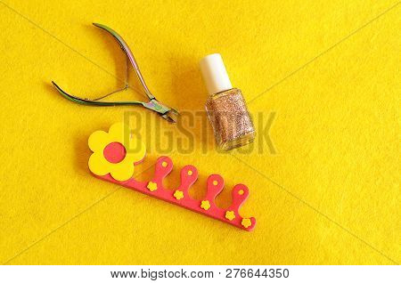 Nail Clipper, Polish And Toe Separator On A Yellow Background