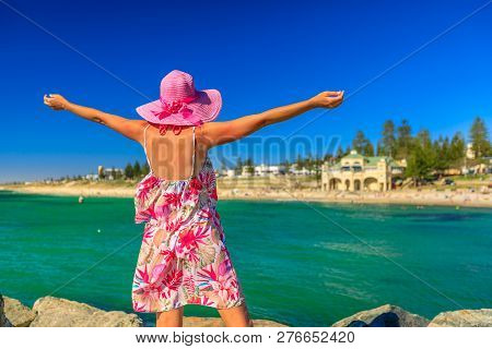 Carefree Woman In Hat With Open Arms At Cottesloe Beach, Perths Most Famous Town Beach, Western Aust