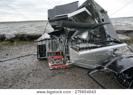 Broken Computer Parts, Monitors And Printers In Front Of Nature Landscape With A River Background. D