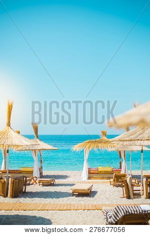 Sunshade Umbrellas And Deckchairs On The Beautiful Beach In Himara, Turquoise Water Of Ionian Sea In