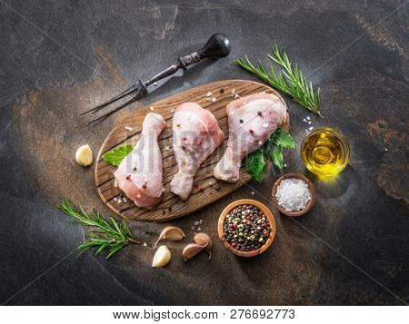 Chicken legs with spices and salt  ready for cooking on cutting board.