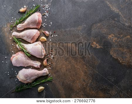 Chicken legs with spices and salt  ready for cooking on cutting board.