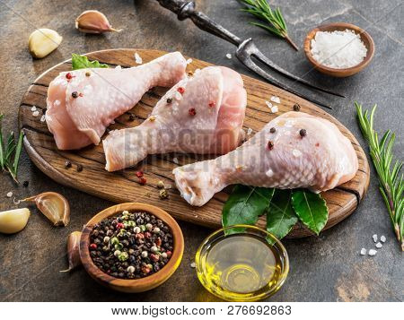 Chicken legs with spices and salt  ready for cooking on cutting board.