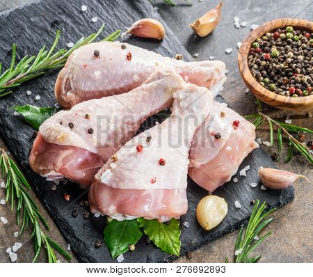 Chicken legs with spices and salt  ready for cooking on cutting board.