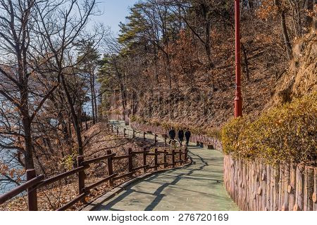 Yesan, South Korea; December, 23, 2018: Three Unidentified People Walking Up Sidewalk In Yesan Lake 