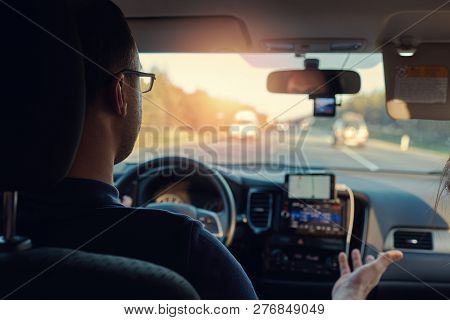 European Man Is Driving The Car, While Explaining Something To His Girlfriend. Insight View.