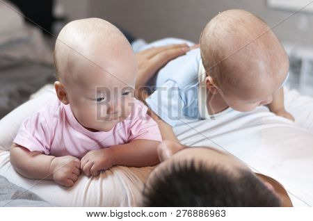 Young Father With His Newborn Twins Lying In Bed. Selective Focus