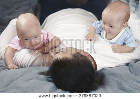 Young Father With His Newborn Twins Lying In Bed. Selective Focus