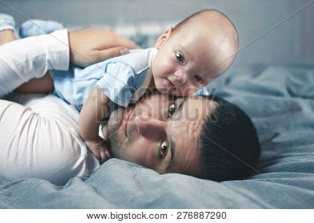 Young Father With His Newborn Son Lying In Bed. Young Father With His Newborn Twins Lying In Bed. Se