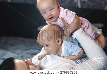 Young Father With His Newborn Twins Lying In Bed. Selective Focus