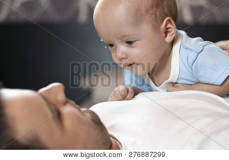 Young Father With His Newborn Twins Lying In Bed. Selective Focus