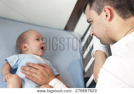 Young Dad Is Tired Of Putting A Small Child To Bed. Dad And Son Fatherly Care Concept. Selective Foc