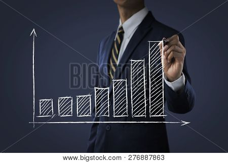 Business Growth, Progress Or Success Concept. Businessman Is Drawing A Growing Bar Graph On Dark Ton