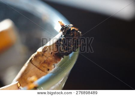 Burnt Cigarette Butt In An Ashtray Lit By The Sun