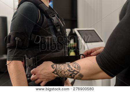 Male Trainer Fastening Belt Of Ems Suit On Woman