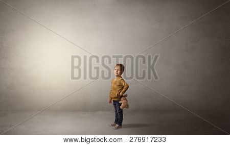 Little waggish kid staying alone in a big empty room with his plush