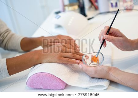 Close-up Of Beautician Applying Cream On Woman's Hand Using Brush.