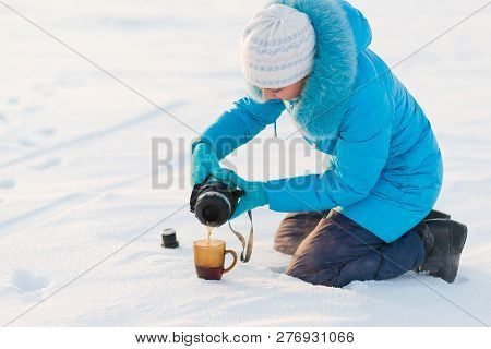 The Girl Pours Tea From A Thermos Into A Mug. Winter Photo