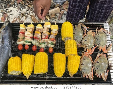Humand Hand Grilling Seafood, Corn And Bbq At The Beach.