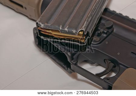 The Upper Of A Black And Brown 223 Caliber Ar-15 Rifle With A Removed, Loaded Rifle Magazine With A 