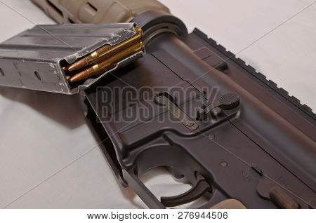 The Upper Of A Black And Brown 223 Caliber Ar-15 Rifle With A Removed, Loaded Rifle Magazine With A 
