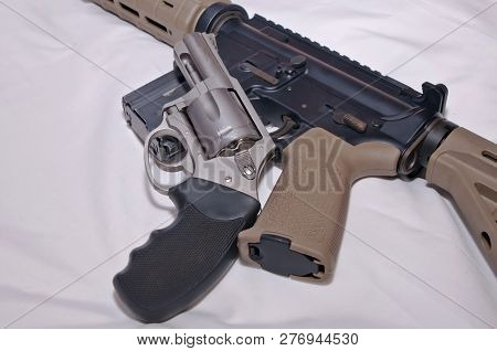A Stainless Steel 357 Magnum Revolver With A Black Grip On Top Of A Black And Brown 223 Caliber Ar-1
