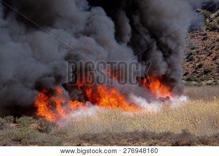 Fierce brushfire with flames and black smoke
