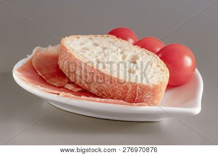 Dry Spanish Ham, Jamon, Italian Ham, Chopped Layers With Bread And Cherry Tomatoes On A White Heart-