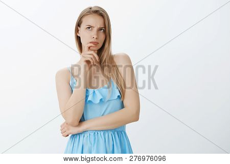 Attractive Glamour European Female With Fair Hair In Blue Dress Trying Think Hard Frowning Touching 