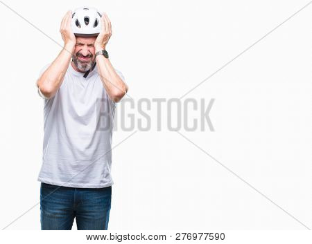 Middle age senior hoary cyclist man wearing bike safety helment isolated background suffering from headache desperate and stressed because pain and migraine. Hands on head.