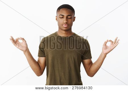 Studio Shot Of Calm And Peaceful Young African American Sportsman Standing In Lotus Pose Searching N