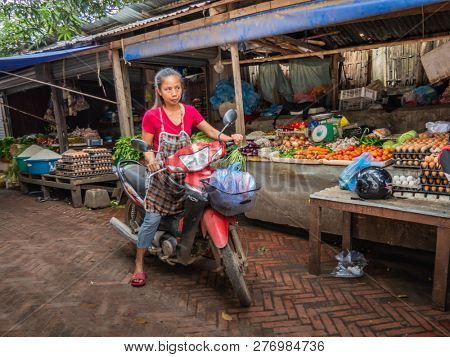 luang prabang, laos - november 20, 2018: woman goes shopping with motorbike at the market in luang prabang.