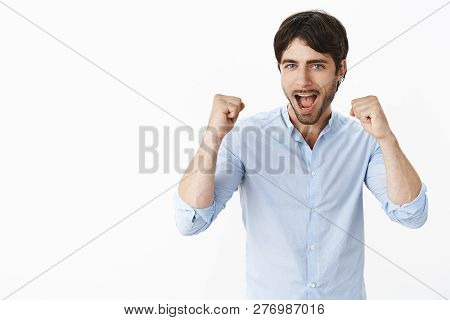 Joyful Excited Good-looking Entrepreneur Cheering And Triumphing Yelling Yes And Raising Clenched Fi
