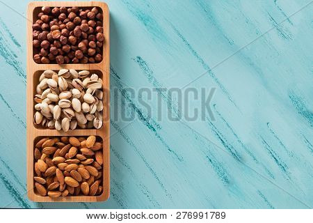 Compartmental Dish With Nuts On Blue Wooden Table. Hazelnut, Almond, Pistachio.