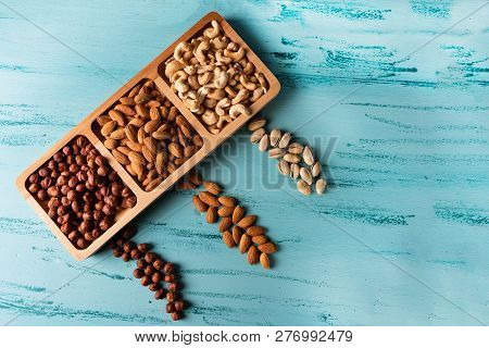 Compartmental Dish With Nuts On Blue Wooden Table. Cashew, Hazelnut, Almond.