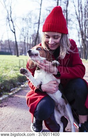 Pretty Young Girl In Redd Coat Playing With Dog Outside In Green Park, Lifestyle People Concept